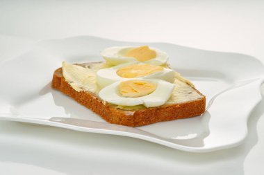 Sandviç ekmeği, tereyağı, yumurta ve peynir Beyaz plaka ve beyaz arka plan, yakın çekim