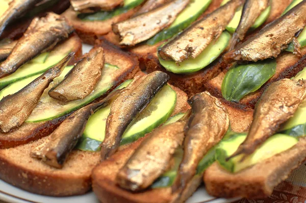 stock image Sprats with cucumber slices on toasted bread, close-up