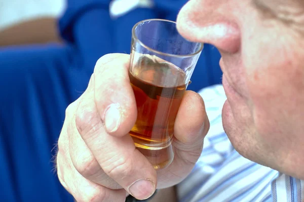 Ein Mann, der Cognac im Glas schnüffelt, in Großaufnahme entschärft — Stockfoto