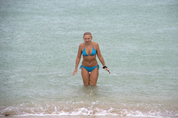 Una mujer rubia en traje de baño azul sale del mar en la ra — Foto de Stock