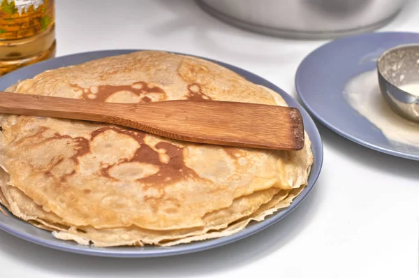 Pfannkuchen auf grauem Teller und Holzpaddel, weißer Hintergrund — Stockfoto