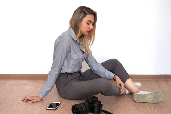 Bella giovane bionda è seduta sul pavimento, accanto al venuto — Foto Stock