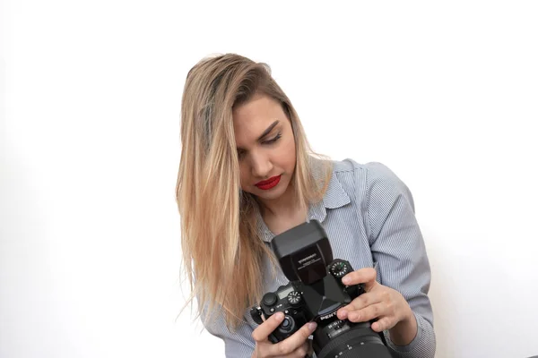 Ung sexy blondine ser på bilder på et studiokamera, hvit rygg – stockfoto