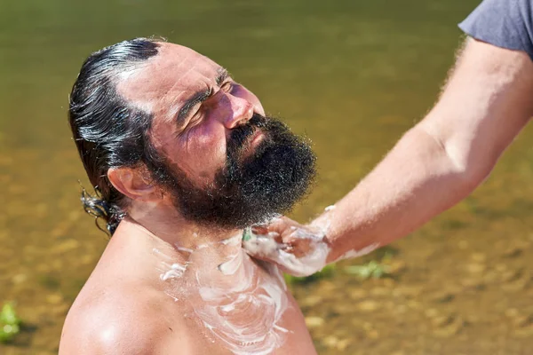 Afeitarse al aire libre, un hombre con una barba negra en el fondo de — Foto de Stock