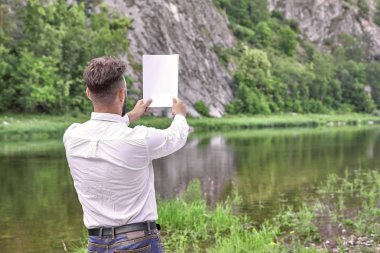 Arkadan gelen genç bir işadamı boş bir pa levha tutuyor.