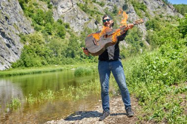 Bir müzisyen arka planda yanan bir akustik gitar oynar 