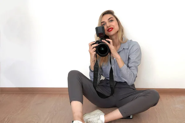 Giovane bionda sorridente siede sul pavimento in studio e tiene un — Foto Stock