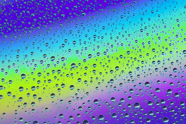 Tropfen auf dem Glas vor dem Hintergrund des Regenbogens, Textur — Stockfoto