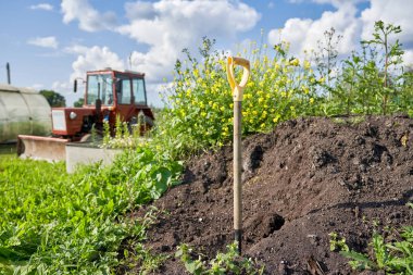 Kürek bir kompost çukuru ve traktör karşı yere sıkışmış