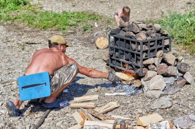 Çıplak gövdeli genç adam kamp banyosu hazırlıyor