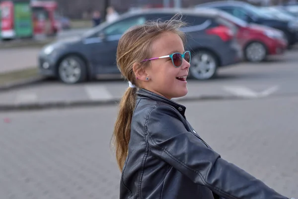 笑的女孩穿着皮夹克和太阳镜在街上 — 图库照片