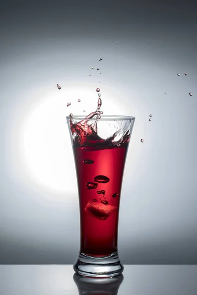 Прозрачный стакан с красным вином, льдом и брызгами света — стоковое фото