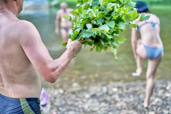 Un homme tient un balai de bouleau pour un bain dans la rivière — Photo