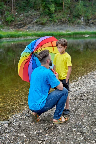 Fête des pères en plein air. Père et fils sous un parapluie de couleur LGBT — Photo