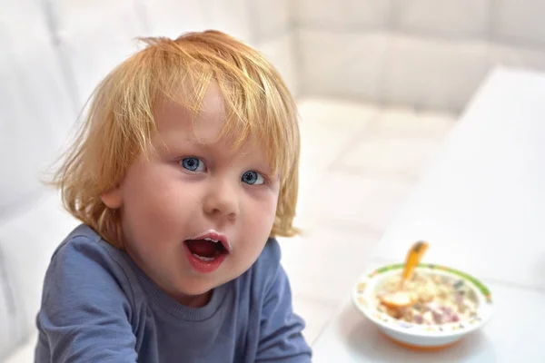 Un bambino di tre anni guarda la telecamera con la bocca op — Foto Stock