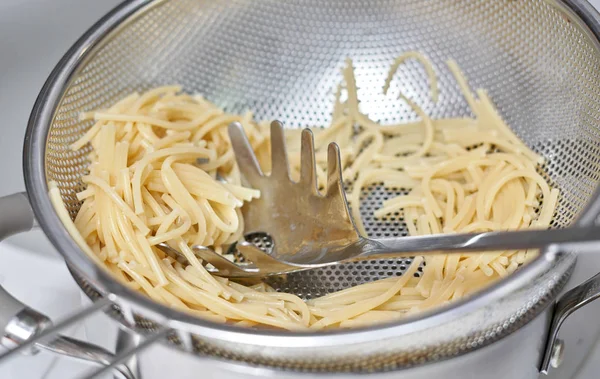 Colador con restos de pasta de espagueti, primer plano sobre una espalda blanca Imagen De Stock