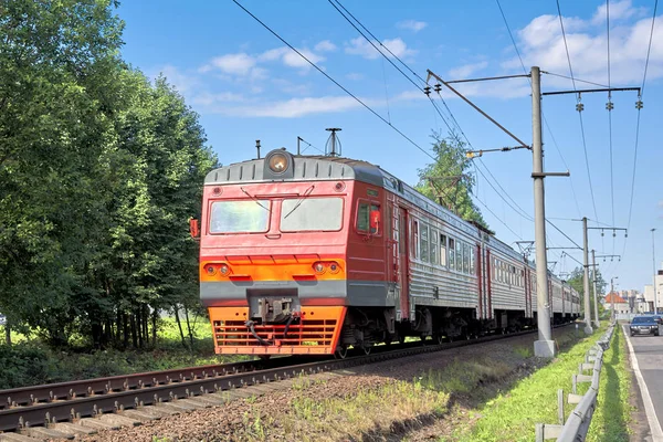 Červený dojíždějící vlak jede na kolejích za letního slunečného dne. Publi — Stock fotografie