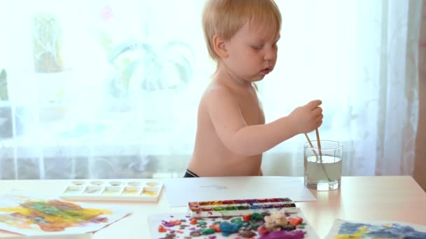 Blonde babe draws paints at a table in kindergarten. — Stock Video