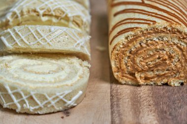 Arka planda koyu ve açık renkli iki bisküvi rulosu. Limonlu somun ve konsantre süt, yakın plan.