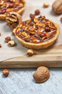 Süt dolu yuvarlak kahverengi kek sepeti. Tahtadaki cevizlerle dolu bir hayat. Dikey çekim, yakın çekim.