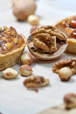 Süt dolu yuvarlak kahverengi kek sepeti. Tahtadaki cevizlerle dolu bir hayat. Dikey çekim, yakın çekim.