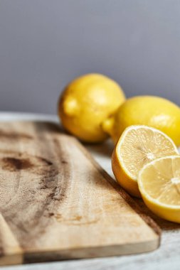 Kirli kesim tahtasının yanındaki sarı limonlar. Mutfakta hala hayat var. Dikey çekim, yakın çekim.