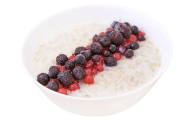 Beyaz yaban mersini kasesinde yulaf ezmesi ve kırmızı frenk üzümü. Kahvaltı için sağlıklı yiyecekler. Beyaz arkaplanda yakın plan.