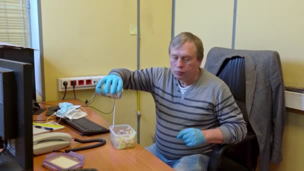 Человек в медицинских перчатках, чтобы поесть на рабочем месте в офисе — стоковое видео