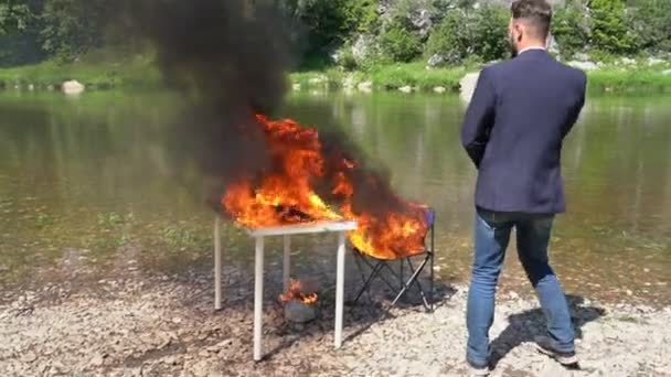 Een kantoormedewerker verbrandt de werkplaats aan de rivier. De meubels in het vuur — Stockvideo