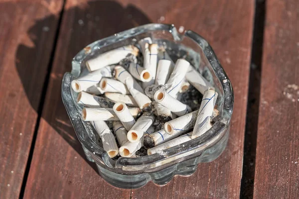 Many Cigarette Butts Ashtray Top View Brown Planks Background Stock Image