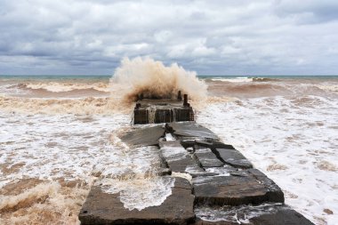 Büyük deniz dalgaları taştan bir dalgaya çarpar.