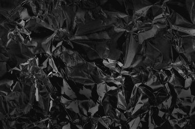 Parlak siyah folyo metal dokusu, arkaplan ve tasarım çalışmaları için soyut ambalaj kağıdı.