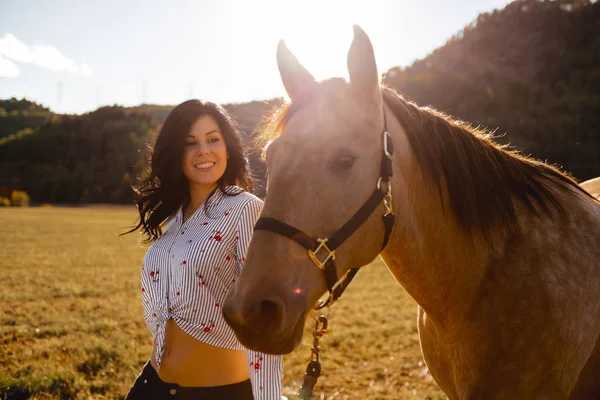 Uma mulher com seu cavalo ao pôr do sol, cena Outono ao ar livre — Fotografia de Stock