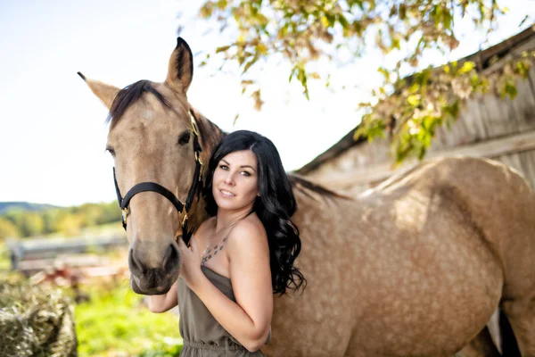 A Portrait of young beautiful woman with brown horse outdoors — Stock Photo, Image