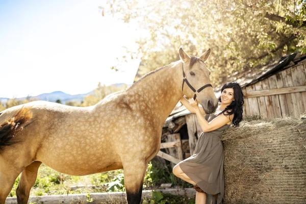 A Portrait of young beautiful woman with brown horse outdoors — Stock Photo, Image