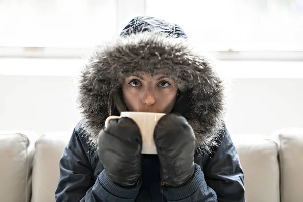 Femme ont café boisson froide sur le canapé à la maison avec manteau d'hiver — Photo