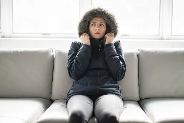 Mujer tiene frío en el sofá en casa con abrigo de invierno — Foto de Stock