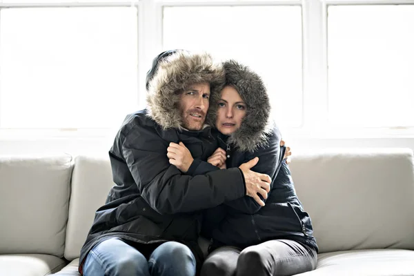 カップルが自宅のソファの上寒い冬のコート — ストック写真