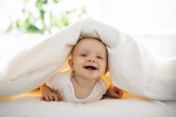 Söt baby flicka liggande på vitt ark hemma — Stockfoto