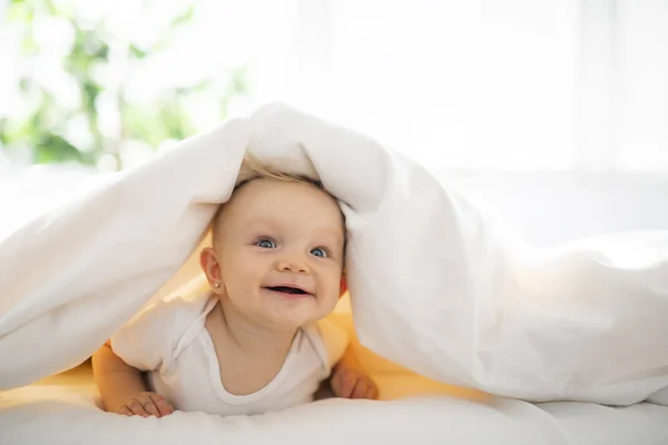 Linda niña acostada en sábana blanca en casa — Foto de Stock