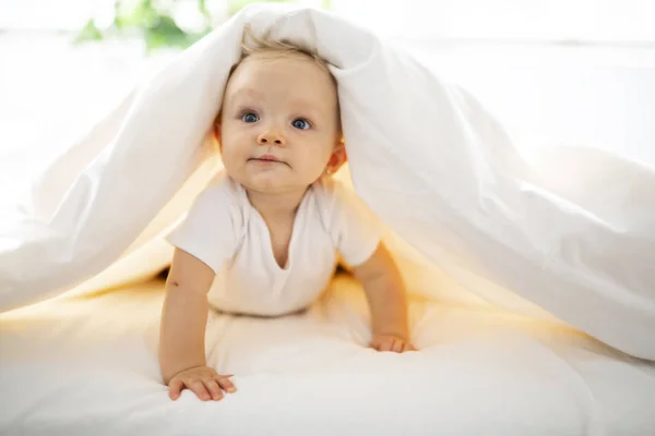 Niedliche Baby-Mädchen auf weißem Laken zu Hause liegen — Stockfoto