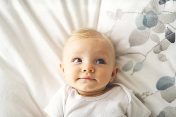 Mignon bébé fille couché sur une feuille blanche à la maison — Photo
