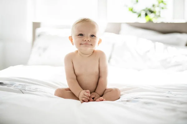 Mignon bébé fille assis sur une feuille blanche à la maison — Photo