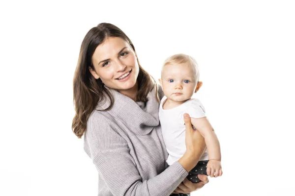 Una madre tiene il suo bambino sullo sfondo bianco dello studio — Foto Stock
