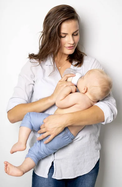 Una madre tiene il suo bambino sullo sfondo bianco dello studio — Foto Stock