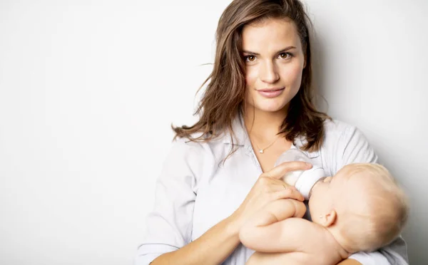 Una madre sostiene a su bebé en el fondo blanco del estudio —  Fotos de Stock