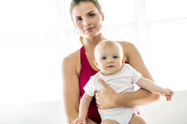 Un ritratto di bella giovane madre in abbigliamento sportivo con il suo piccolo bambino affascinante in sessione di allenamento — Foto Stock