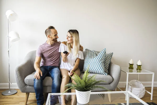 Couple watching tv at home sitting in a comfortable couch in the livingroom at home