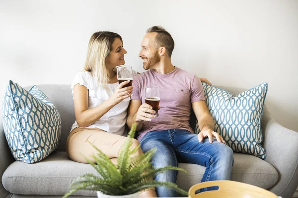 Relajada pareja joven viendo la televisión y bebiendo cerveza en casa — Foto de Stock
