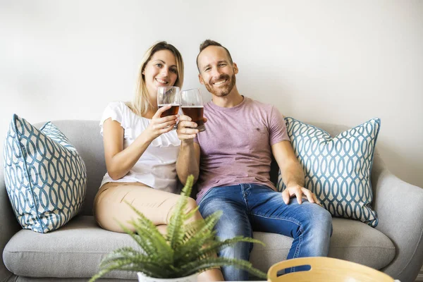 Relajada pareja joven viendo la televisión y bebiendo cerveza en casa — Foto de Stock